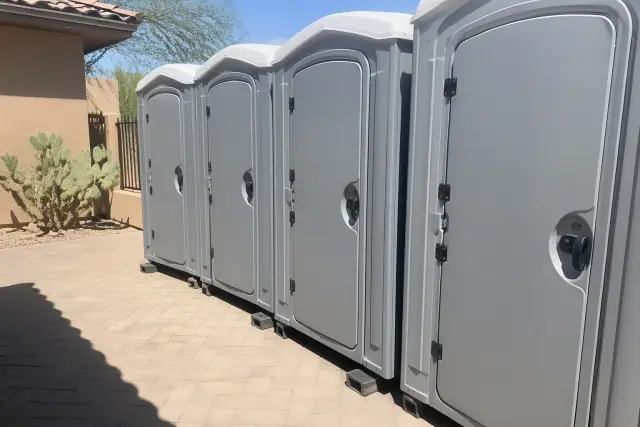 Portable event toilets set up on a paver patio at an outdoor venue in Chandler, AZ.
