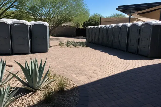 Portable toilets arranged on an interlocking paver patio at an outdoor venue in Phoenix, AZ.