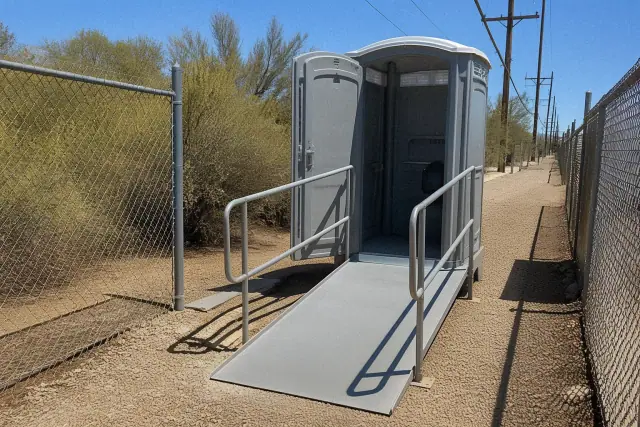 ADA-compliant portable toilet with ramp access on a gravel utility path in Phoenix, AZ.
