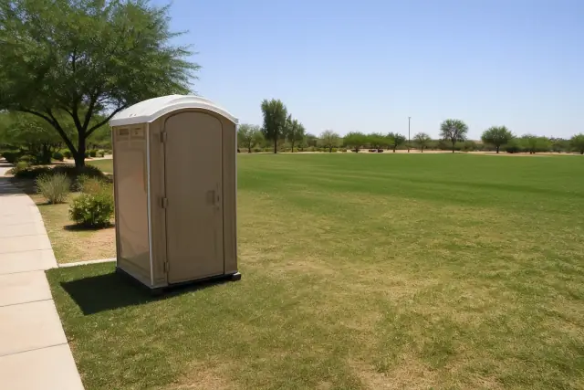 A portable toilet unit placed on a grassy field with desert landscaping in Phoenix, AZ.