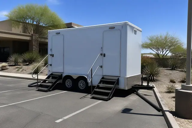 Two-stall luxury restroom trailer parked on an asphalt lot with desert landscaping in Phoenix, AZ.