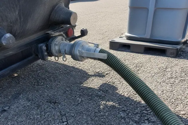 Vacuum truck pump-out connection with a hose and coupling on a gravel jobsite in Phoenix, AZ.