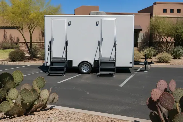 Luxury restroom trailer placed on a paved asphalt parking lot with prickly pear cacti in Phoenix, AZ.