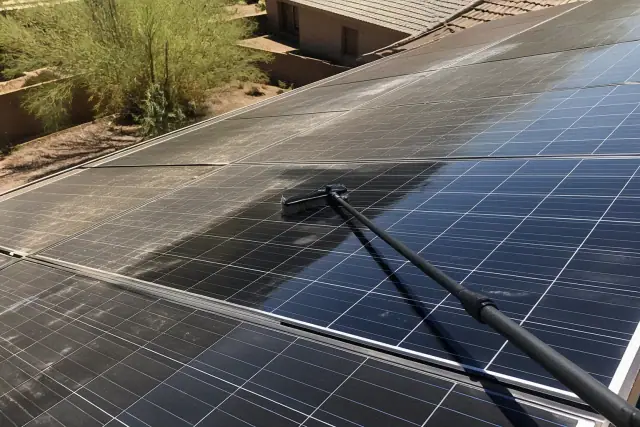A technician cleaning bird droppings from a residential solar panel in Phoenix, AZ.