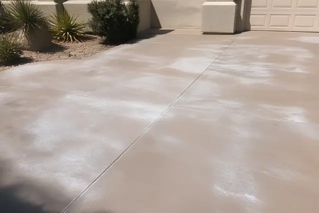 Milky, uneven sealer blotches on a residential concrete driveway in Phoenix, AZ.