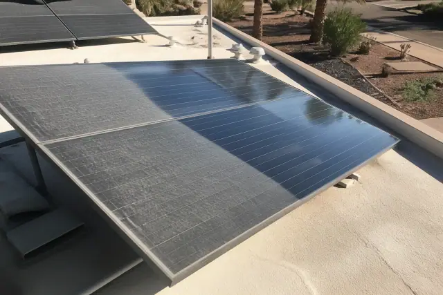 A dusty solar panel array on a flat roof being cleaned under intense sunlight in Phoenix, AZ.