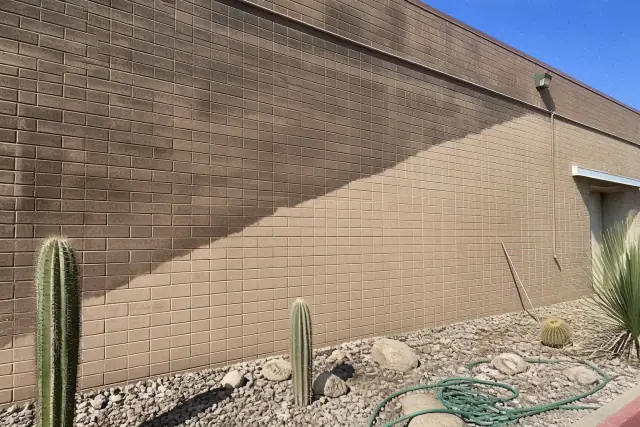 A diagonal line on an industrial building wall in Phoenix, AZ, showing the difference between dirty and cleaned brick.