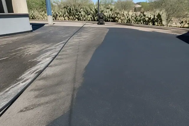 Asphalt parking lot in Phoenix, AZ after pressure washing to remove oil stains, with prickly pear cacti in the sunlight.