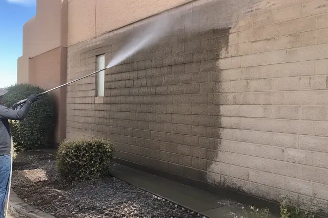 Pressure washing a brick wall at a commercial building in Gilbert, AZ.