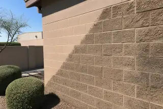 Restored masonry brick wall showing a diagonal line between weathered and cleaned sections in Phoenix, AZ.