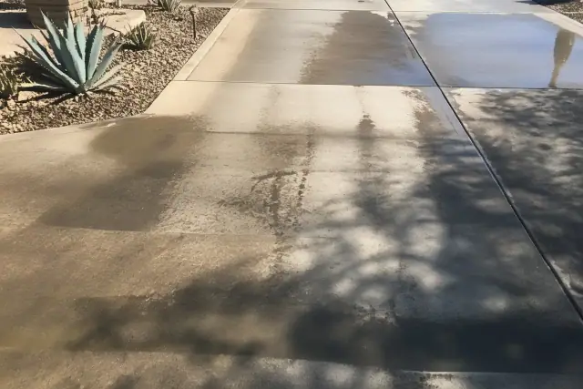Clean stripes from surface cleaning on a residential concrete driveway in Phoenix, AZ, showing oil stain removal.