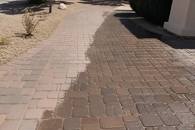 A professional cleaning application on a stone paver walkway in Phoenix, AZ, showing wet, saturated tiles.