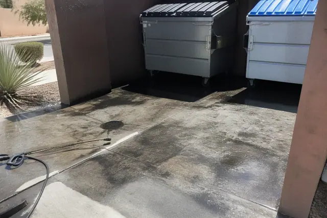 Concrete dumpster pad showing grease and grime removal in a Phoenix, AZ waste enclosure.