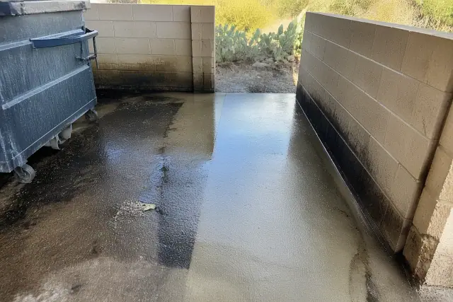 Pressure washing a greasy dumpster pad and drive-thru area in Buckeye, AZ, showing clean concrete paths.