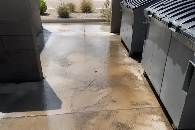 Pressure washing a commercial dumpster pad with grease and grime removal in Gilbert, AZ.
