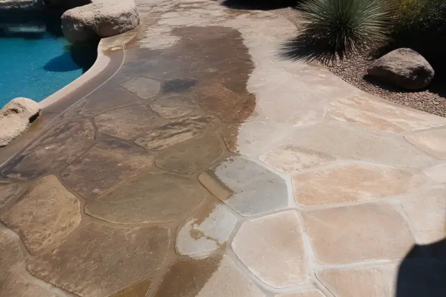 Partially cleaned flagstone, slate, and natural stone pool deck in the sun in Phoenix, AZ.