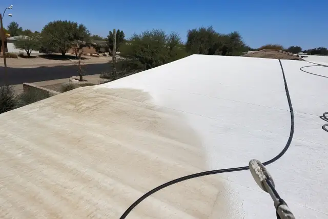 Foam roof being cleaned under intense sunlight in Phoenix, AZ, showing the difference between dirty and clean sections.