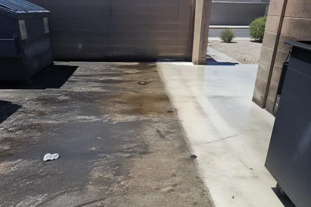 Concrete dumpster pad showing cleaned areas next to grease stains at a commercial site in Phoenix, AZ.