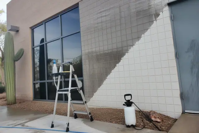 Technician cleaning glass, tile, and finished metal on an industrial building in Phoenix, AZ.
