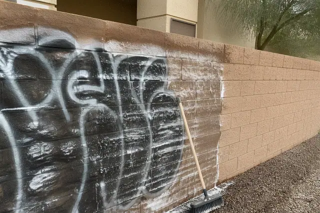 A brick wall in Tempe, AZ, showing the process of removing graffiti with a scrub brush and solvent.