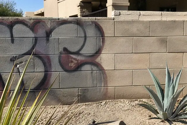 Pressure washer cleaning graffiti off a masonry wall at a residential site in Peoria, AZ.