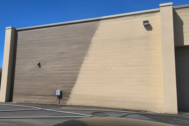 A side-by-side view of dirty and cleaned brick masonry during a soft washing job on an industrial building in Phoenix, AZ.