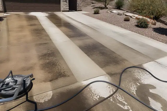 Concrete driveway in Phoenix, AZ showing clean stripes from surface cleaning on oil and rust stains.