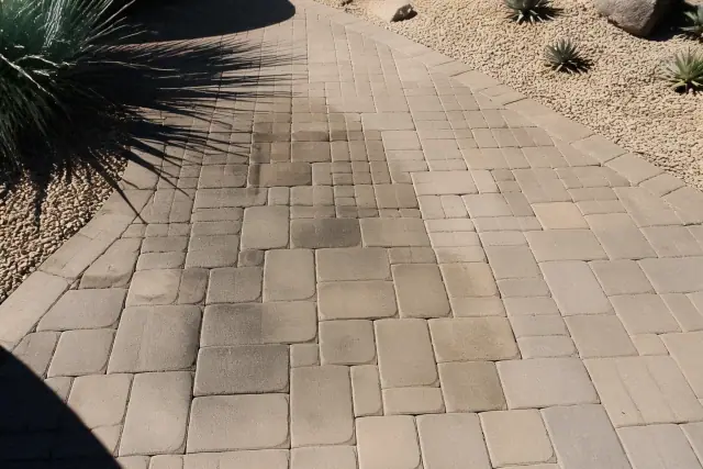 Oil-stained stone pavers on a walkway in Phoenix, AZ, showing dark greasy spots before cleaning.