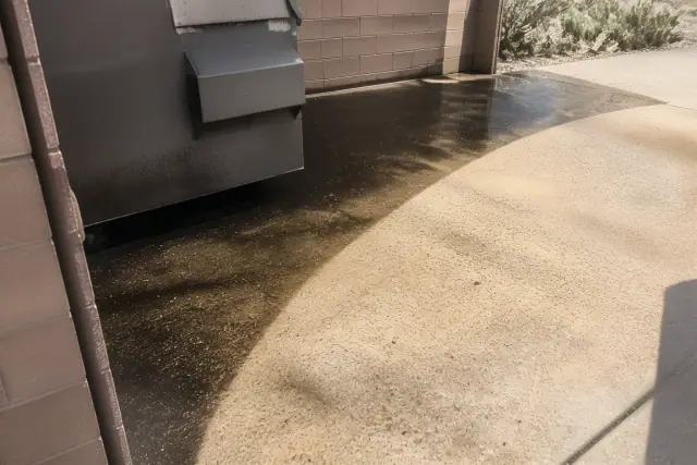 Pressure washing a commercial dumpster pad with grime removed from concrete in Buckeye, AZ.