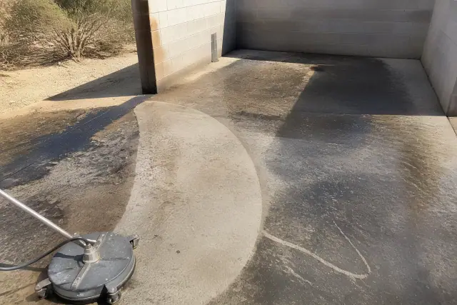 Cleaned path on a concrete dumpster pad in Goodyear, AZ, showing grease removal under bright sunlight.