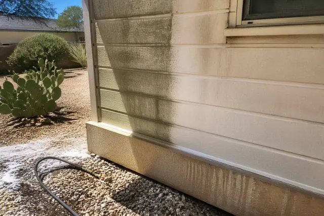 A section of residential siding in Phoenix, AZ, showing clean panels alongside mildew during a house washing project.