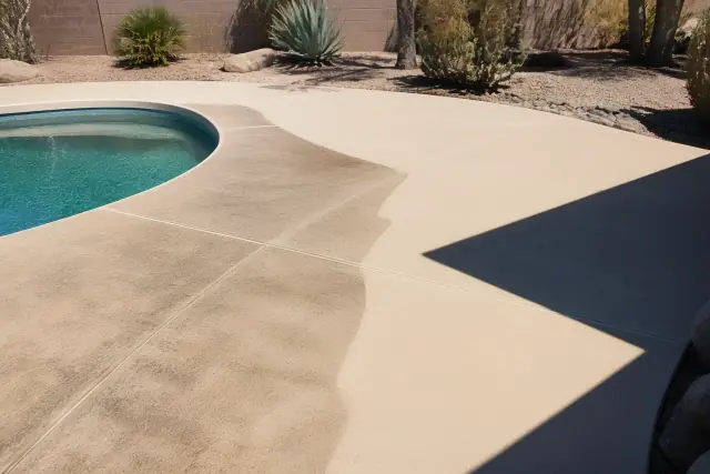 Cleaned pool deck section next to stained concrete with desert landscaping in the background in Phoenix, AZ.