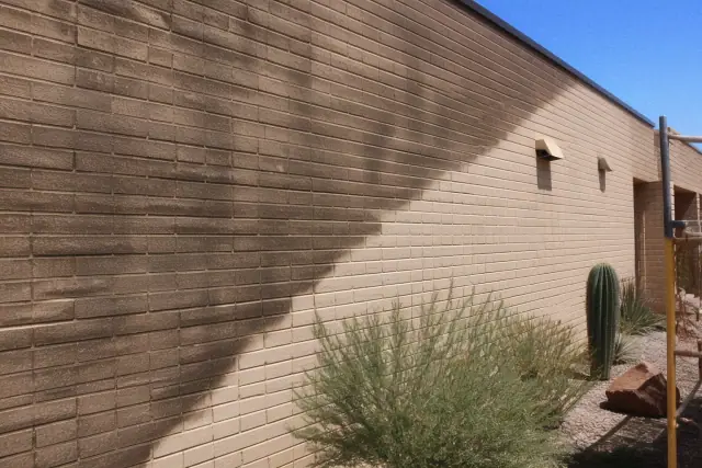 A diagonal line showing clean restored masonry against weathered brick on an industrial wall in Phoenix, AZ.