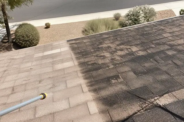A clean section of roof shingles next to algae-stained shingles during a pressure washing job in Surprise, AZ.