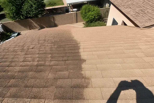 Asphalt shingle roof in Mesa, AZ showing the contrast between cleaned sections and black algae streaks.