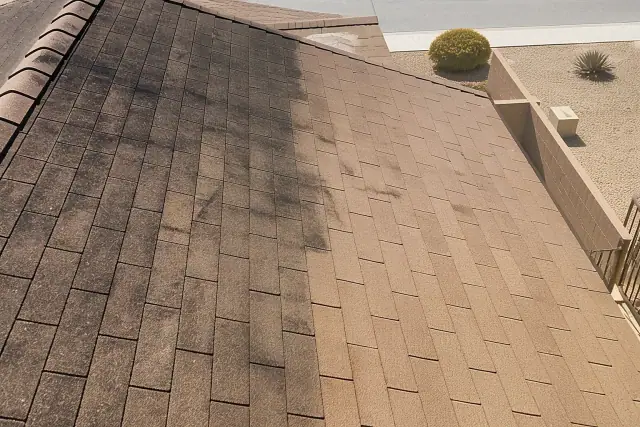 Asphalt roof shingles in Phoenix, AZ showing a contrast between black algae streaks and a freshly cleaned section.