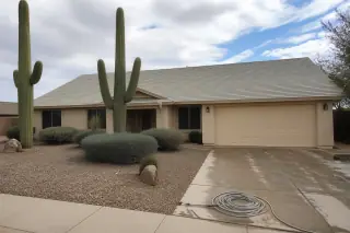 Cleaned asphalt-shingle roof on a single-story home with a coiled wash hose in the driveway, Phoenix, AZ.