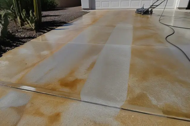 Concrete driveway in Phoenix, AZ undergoing rust and mineral deposit removal showing partially cleaned stripes and stains.