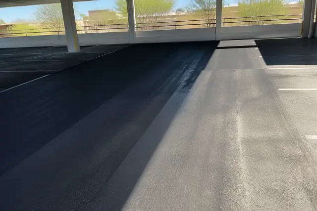 Cleaned asphalt surface in a Phoenix, AZ parking garage showing the contrast between removed stains and pavement.