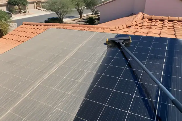 A soft-bristle brush rests on a solar panel during a cleaning job on a terracotta roof in Tempe, AZ.