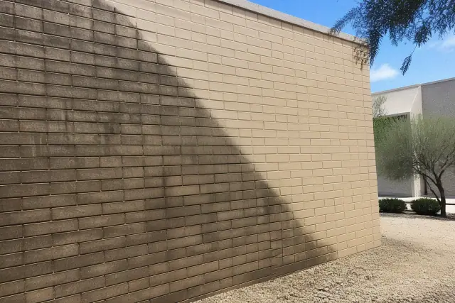 A close-up of a brick wall in Phoenix, AZ showing a diagonal line between dirty weathered brick and cleaned masonry.
