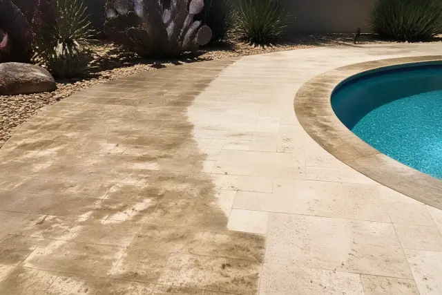 Wet travertine and calcareous stone pool deck undergoing cleaning in Phoenix, AZ with prickly pear cactus in the background.