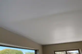 Seamlessly blended drywall ceiling patch illuminated by desert sunlight in a Phoenix, AZ home.