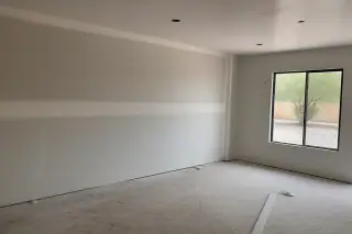 Sanded drywall seam with feathered edges visible through a window in a Phoenix, AZ home.