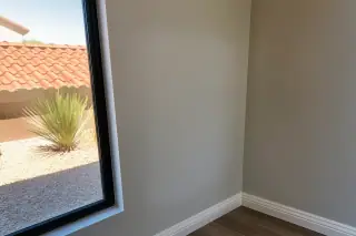 Feathered drywall patch showing sanding residue with a view of desert landscaping through a window in Phoenix, AZ.