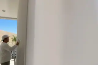 Smooth, sanded drywall seam transition with a technician wiping dust in a home in Phoenix, AZ.