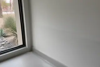 Sanded drywall joint with white dust on the floor near a window in a Phoenix, AZ home.