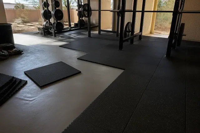 Technician installing heavy-duty rubber floor tiles in a Gilbert, AZ gym.