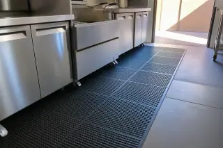 Black anti-fatigue rubber mats installed by stainless steel counters in a commercial kitchen in Phoenix, AZ.