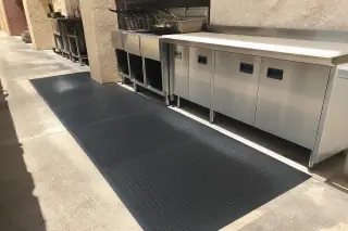 Black anti-fatigue rubber mats installed in a Phoenix, AZ kitchen with stainless steel fryers and desert sunlight.